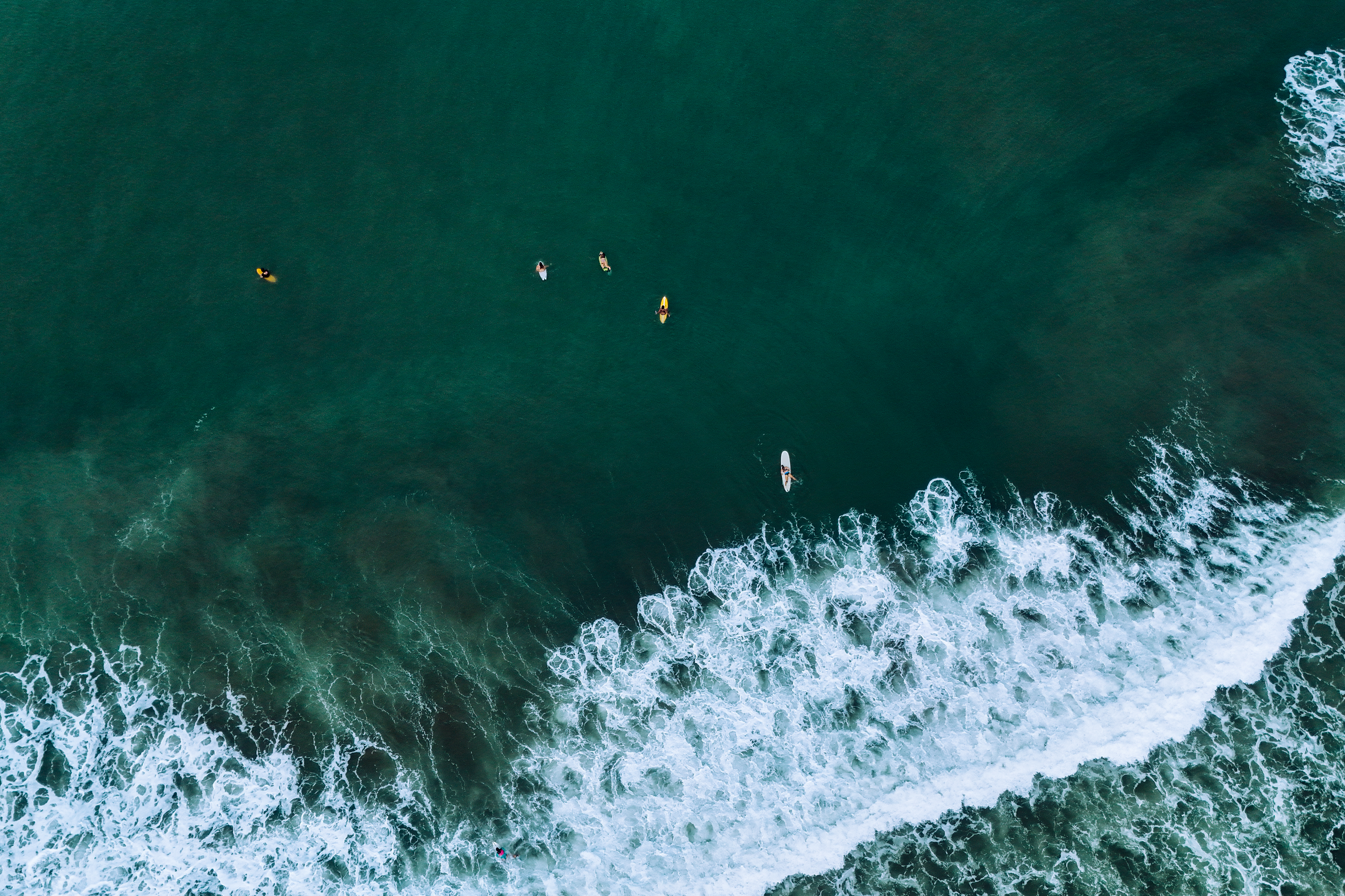 Aerial view of white sea foam over deep teal ocean water